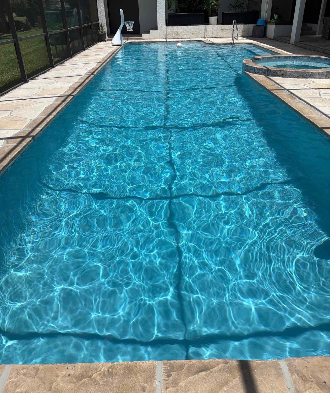 Clear screened residential pool with attached spa after routine pool service